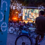 Cinebike Festival 2025 a Palmanova e sul Collio – Vivi in bici l’emozione del cinema all’aperto Potrebbe essere un'immagine raffigurante 4 persone, bicicletta, folla e testo