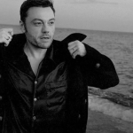 Servizio Bus per Tiziano Ferro Potrebbe essere un'immagine in bianco e nero raffigurante 1 persona e barba